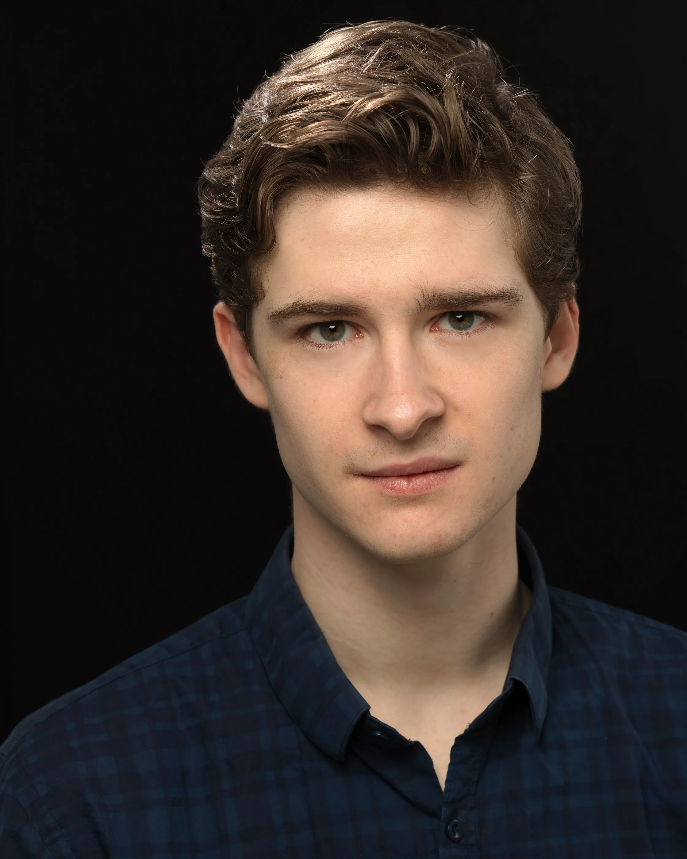 Studio headshot of Andrew Hardigg against a black background, looking directly at the camera